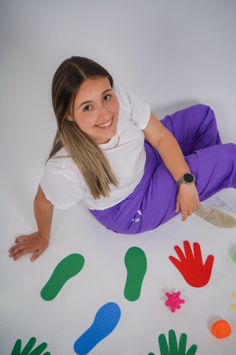 Margarida Pereira no chão, rodeada de pegadas e mãos coloridas usadas em sessão