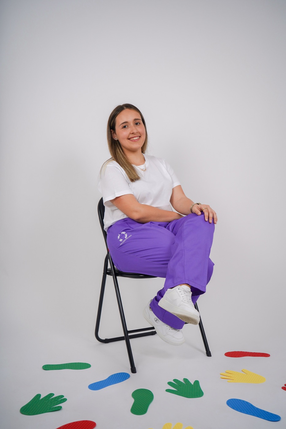 Margarida sentada, com pegadas coloridas no chão à sua frente